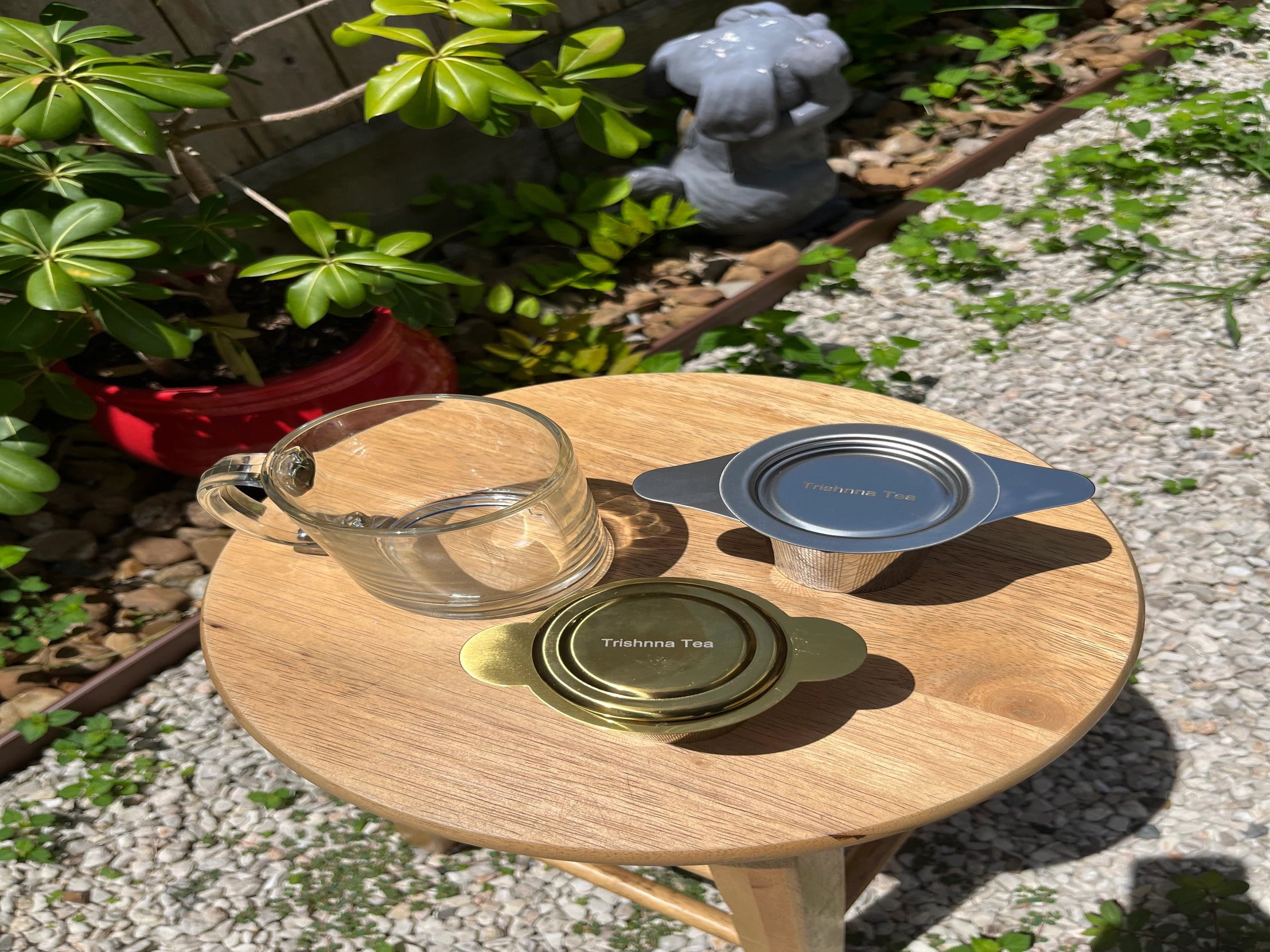 Wooden tray with glass and metal tea infusers on a garden path