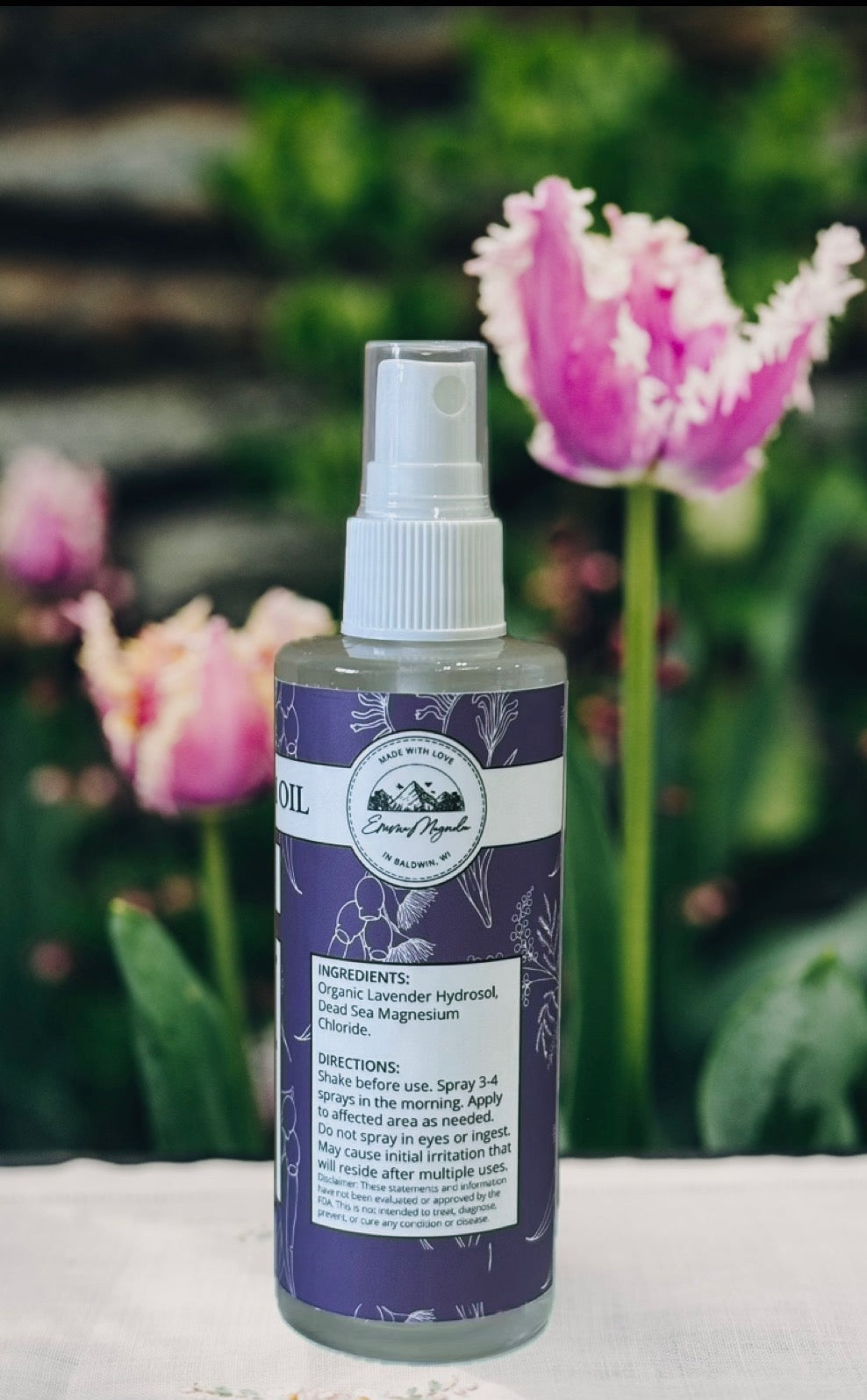 Bottle of organic lavender hydrosol with tulips in the background