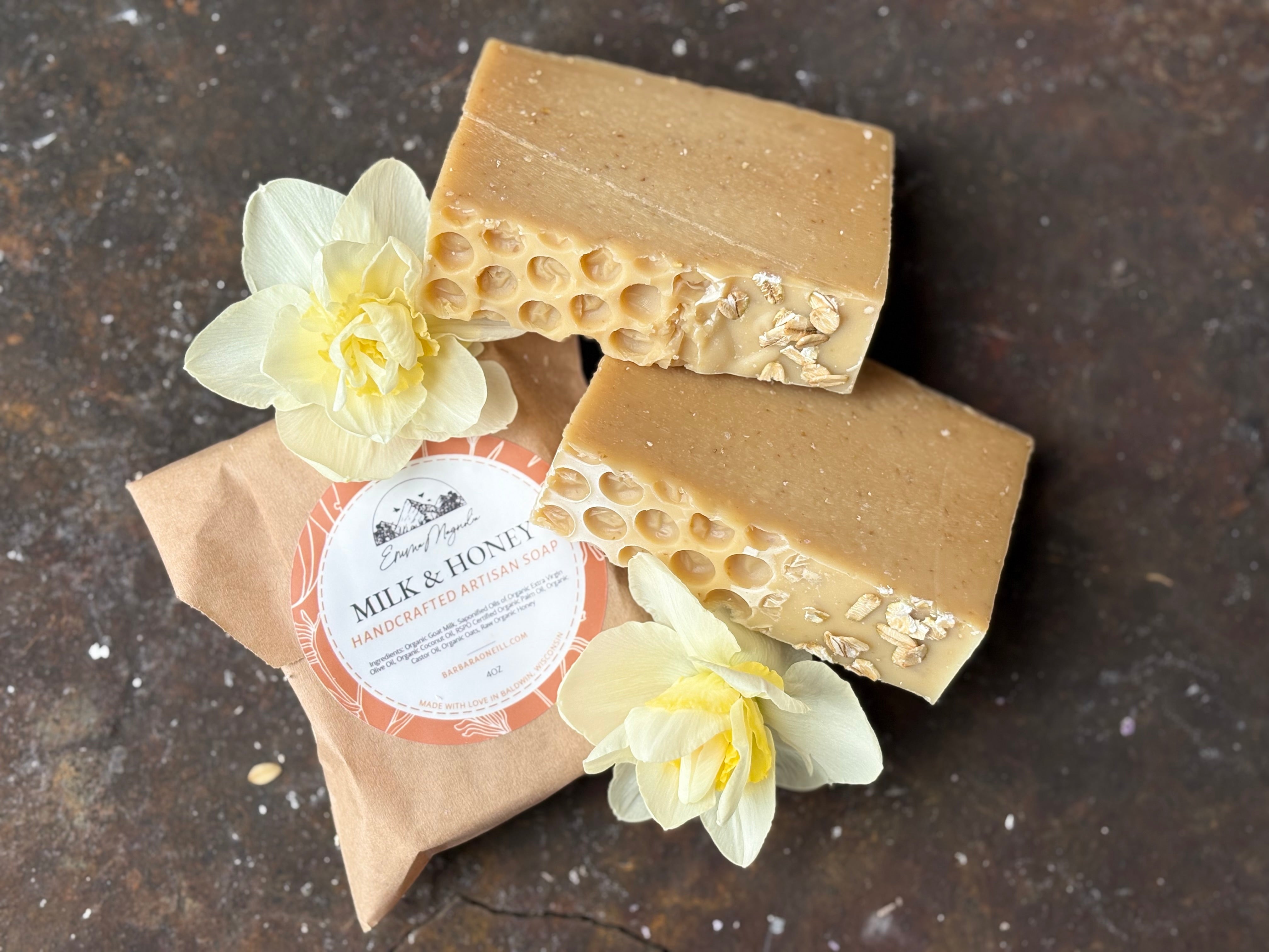 A bar of artisan soap with a honeycomb pattern on top, wrapped in brown paper with a label, accompanied by yellow flowers.