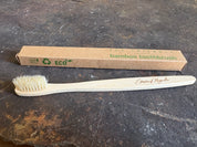 Bamboo toothbrush with 'Eco-Friendly' packaging on a dark surface