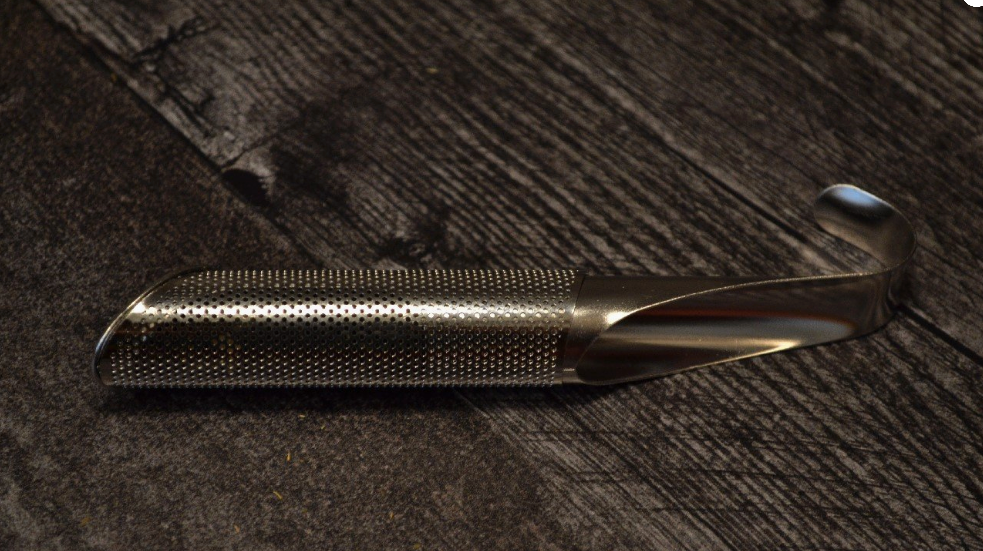 Metallic tool with textured surface on a wooden background