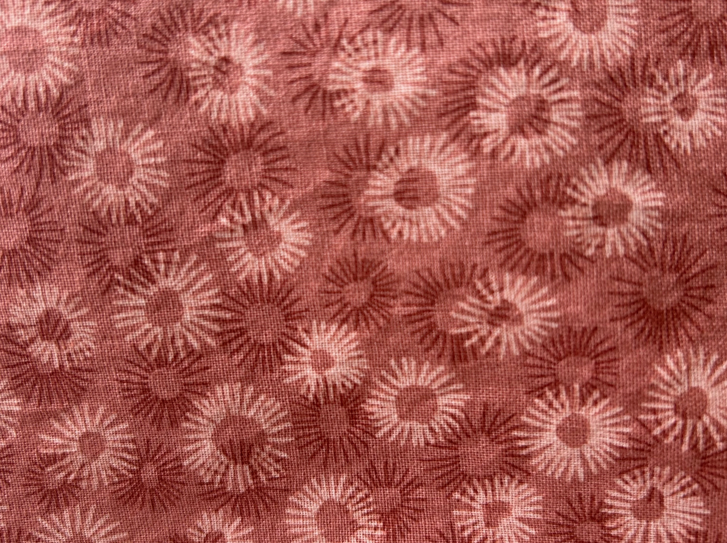 Patterned fabric with sunflower design on a red-brown background