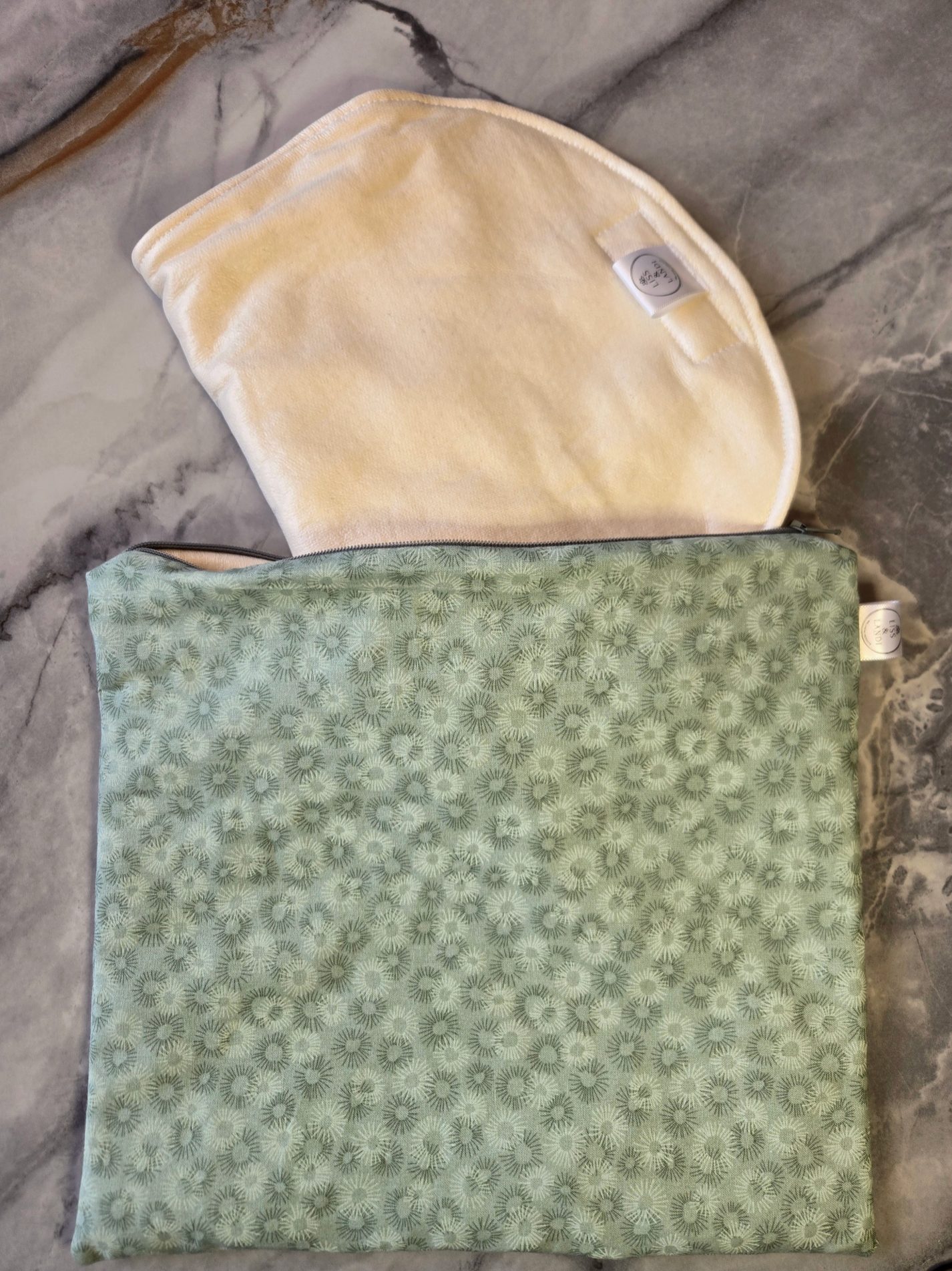 Beige castor oil pack on top of a green floral-patterned fabric on a marble surface