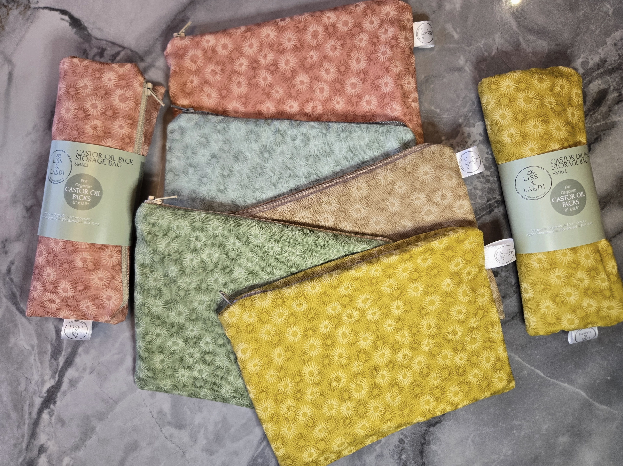 Set of patterned castor oil packs with visible branding on a gray surface