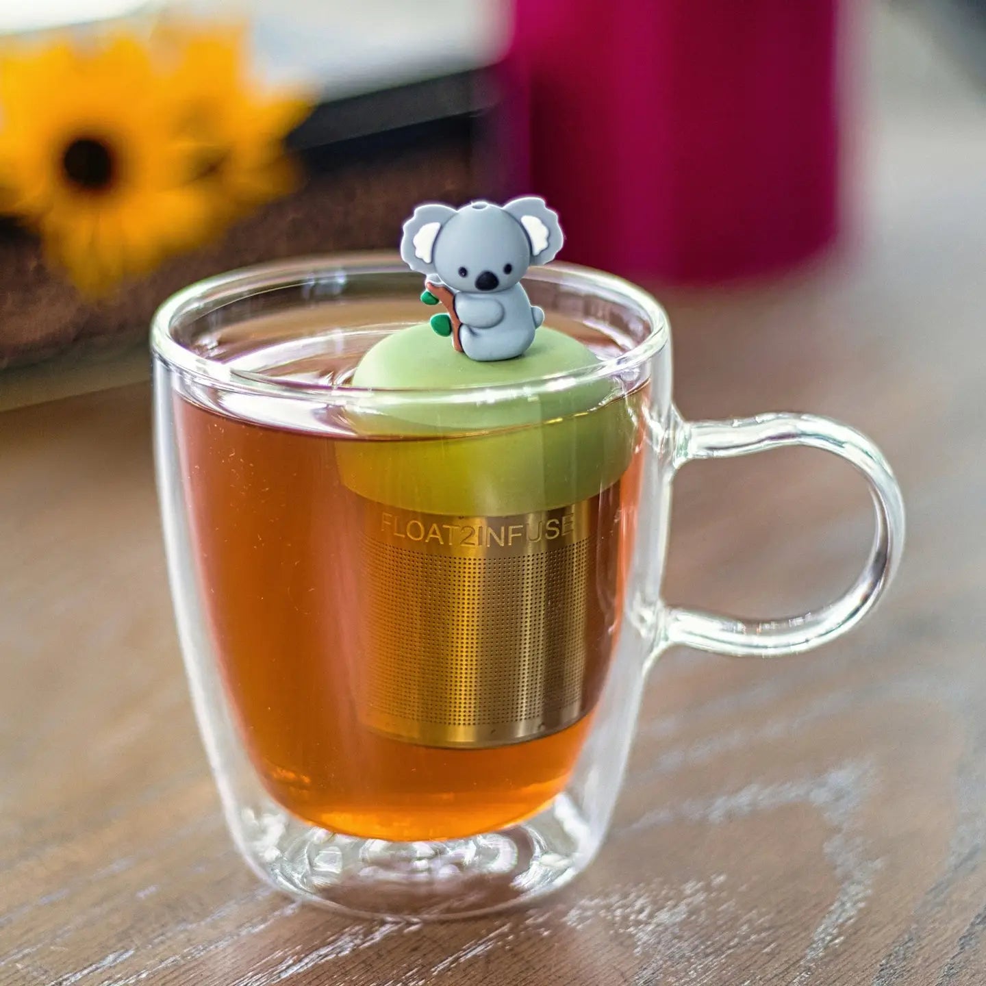 Clear glass mug with a tea infuser featuring a koala design on a wooden surface.